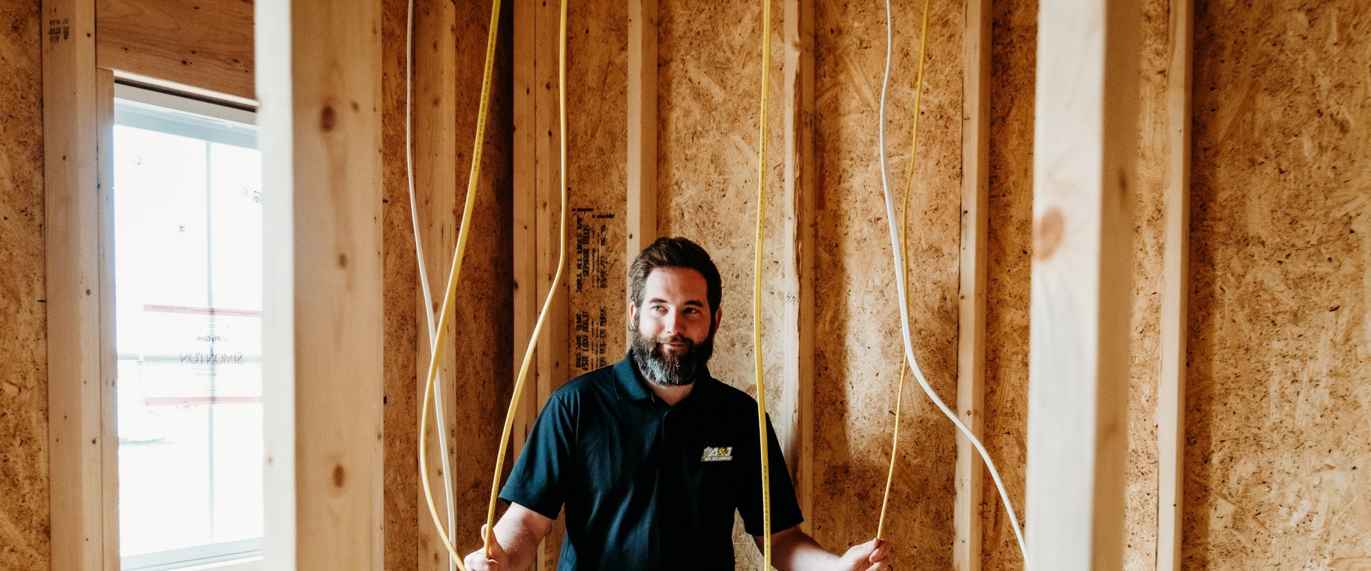 Adam Boyd standing among yellow electrical wire runs on a job site